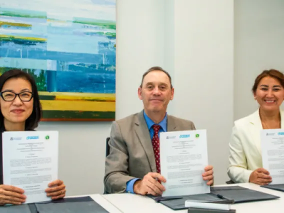 Three individuals hold up signed meemorandums