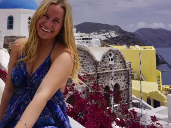 Kylie sitting on a wall with the city of Santorini, Greece behind her