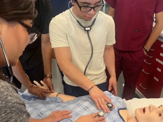 Students from the Universidad del Valle de México use stethoscopes on a practice figure. 