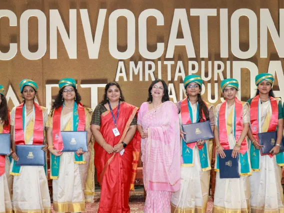 Amrita students hold diplomas and smile.