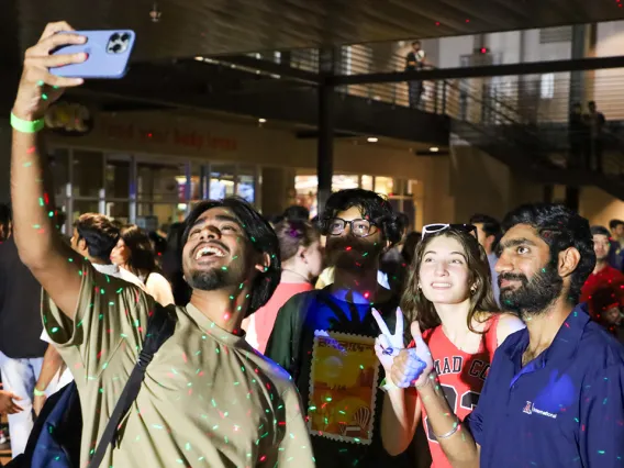 A group of people happily taking a selfie at a lively outdoor event.