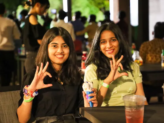 Two students give the Wildcat hand sign while smiling at the camera.