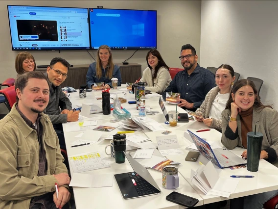 The international admissions team sits around a table smiling at the camera.