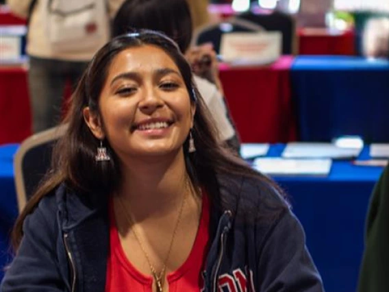 Students smiling at the camera while sitting at a table.