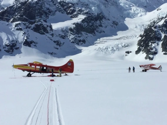 Two planes on the ground in a snowy mountain area.