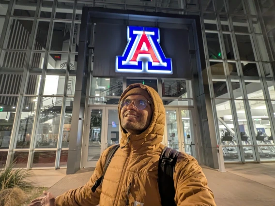 Shreyas in front of a building with a glowing block A.