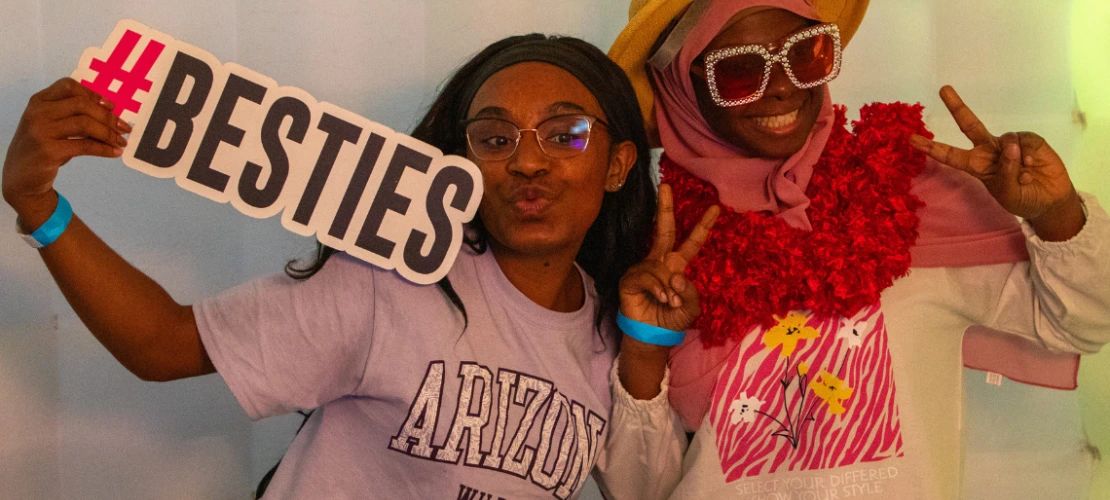 Two student pose for a photo in the photobooth