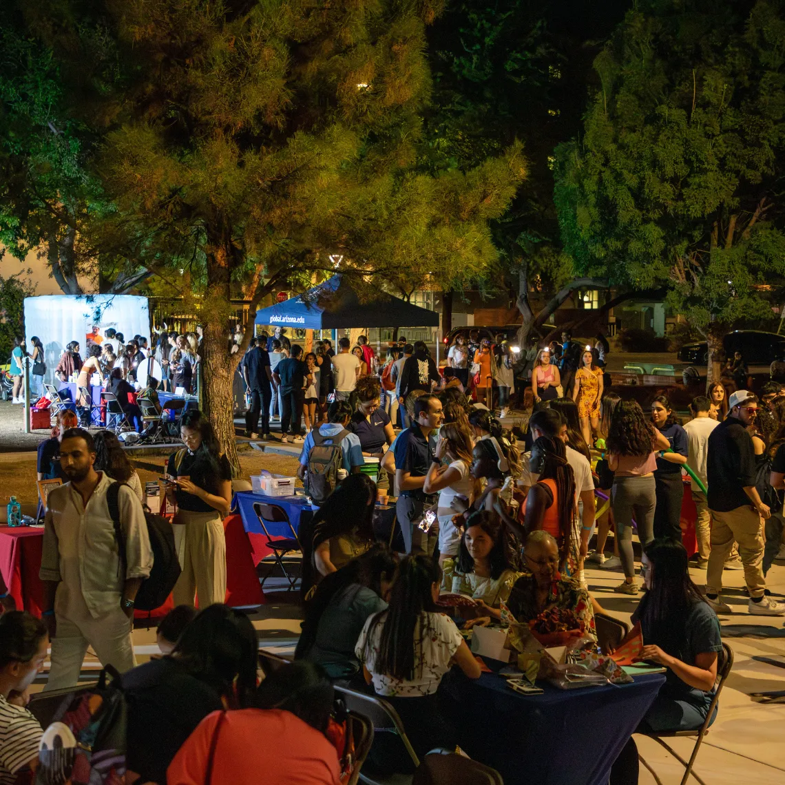 Students gathered around tables in the courtyard of the Global Center