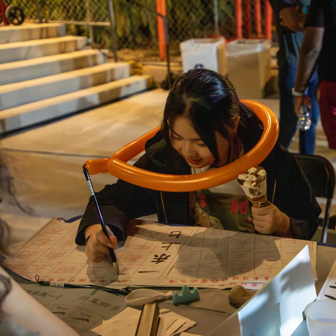 Student does calligraphy while holding an ice cream cone