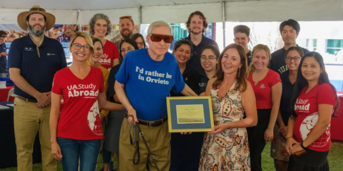 Dr. David Soren holds his plaque while standing with study abroad staff and volunteers.