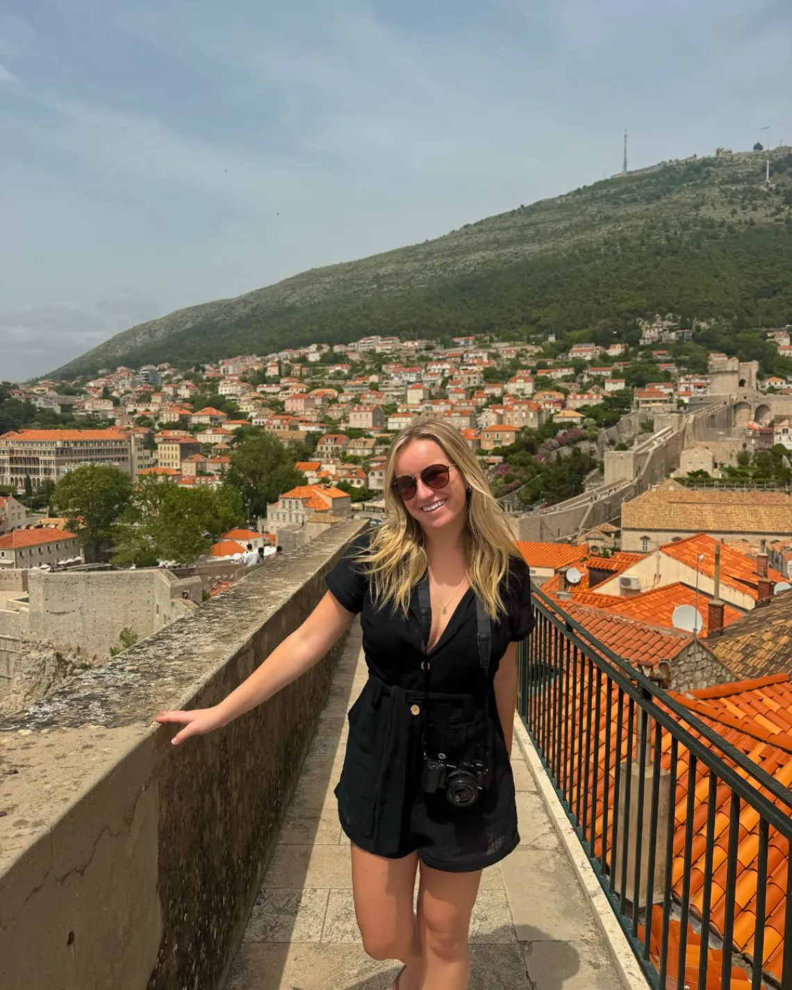 Kylie stands on a bridge with Dubrovnik, Croatia behind her