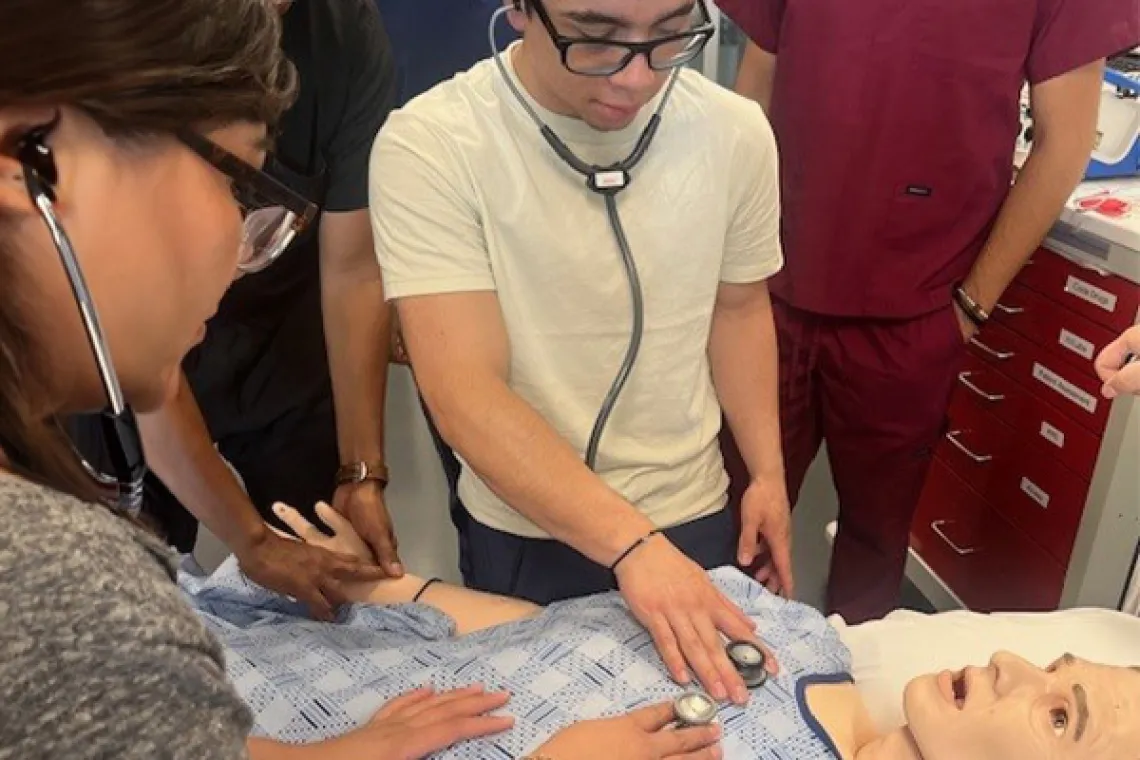 Students from the Universidad del Valle de México use stethoscopes on a practice figure. 