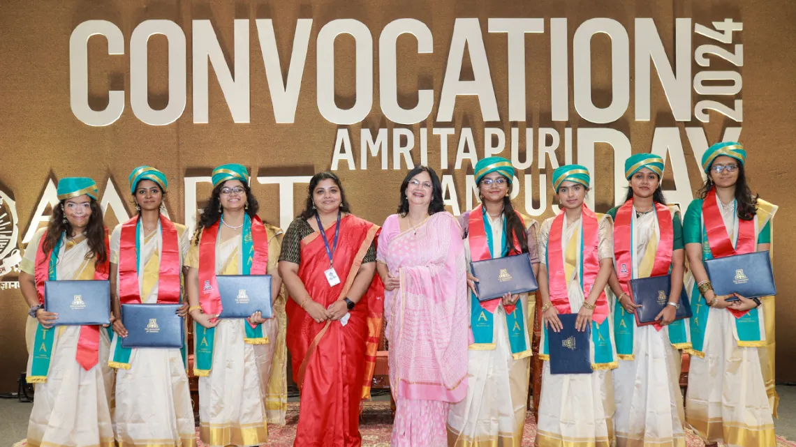 Amrita students hold diplomas and smile.