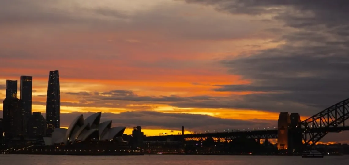 The sun sets behind the Sydney skyline