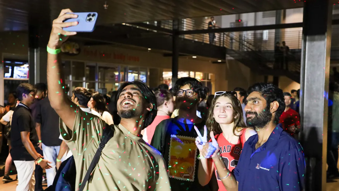 A group of people happily taking a selfie at a lively outdoor event.