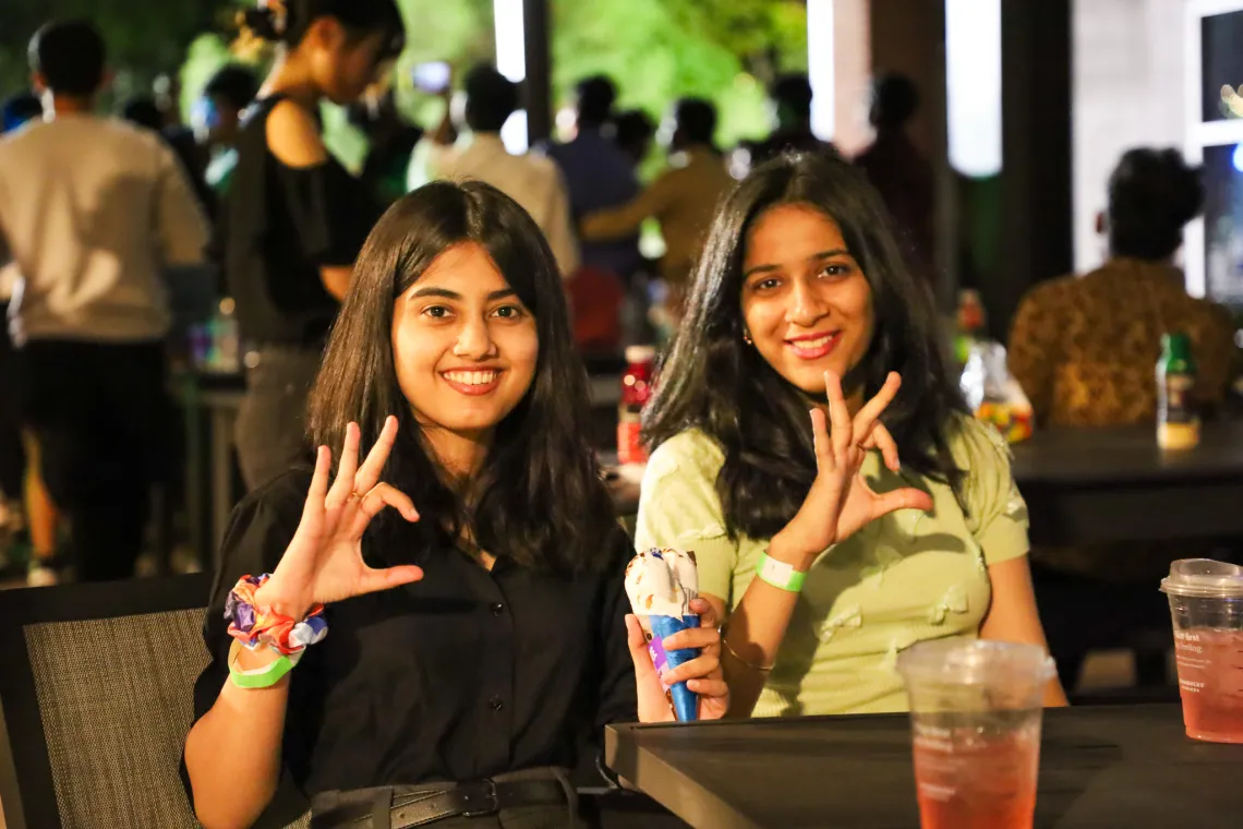 Two students give the Wildcat hand sign while smiling at the camera.