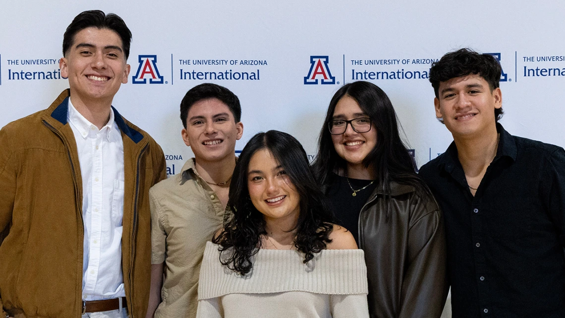 International graduates smile at the camera.