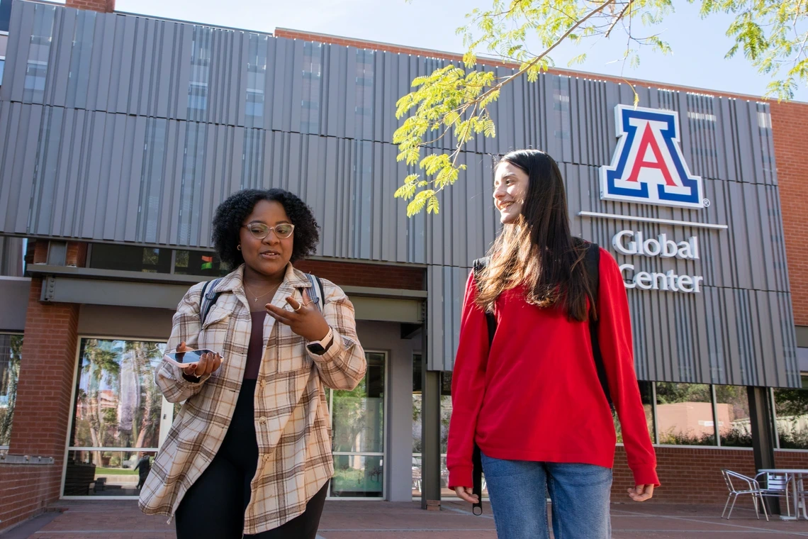 University of Arizona graduates Jennifer Gwasira, left, and Ana Lucia Velazquez Encinas chat as they leave the U of A Global Center