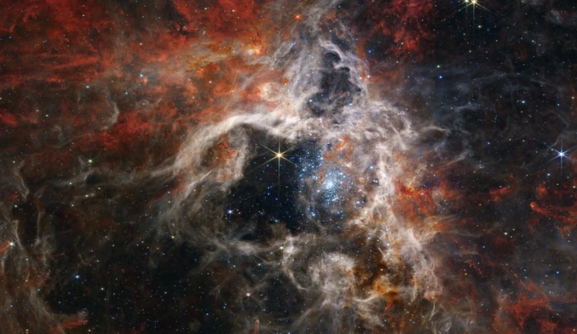 A stunning image of a dense star-forming region in space, filled with swirling clouds of gas and dust illuminated by clusters of bright stars, captured by NASA’s James Webb Space Telescope.