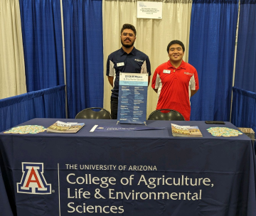 Nguyen and another UArizona student posing behind a CALES table