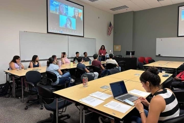 Students in a classroom looking at a woman speaking.