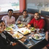 U of A international students sit at a table and smile at the camera