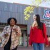 University of Arizona graduates Jennifer Gwasira, left, and Ana Lucia Velazquez Encinas chat as they leave the U of A Global Center