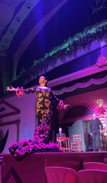 A woman spreads her arms on stage during a flamenco performance