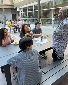 Five students sit at a table outside