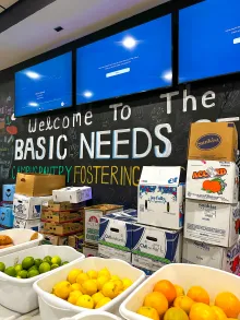 Produce in bins placed in front of a sign that reads Welcome to the basic needs Campus Pantry.