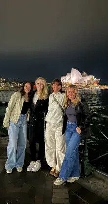 A group of females stand in front of the Sydney Opera House.