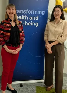 Dr. Angela Dawson and Dr. Sarah Yeo stand together in front of a blue banner.