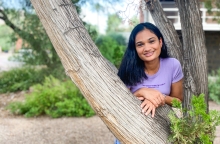 Ananya leans on a branch of a tree near Old Main on the UArizona campus. 