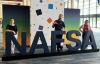Three AZI staff members standing behind large letters spelling NAFSA