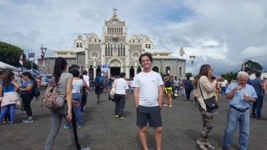 UA Study Abroad Student Brenden Barness standing in a populated town square in Costa Rica with a Basilica behind him