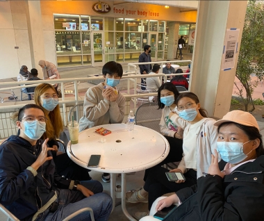 Group of UArizona international students sitting at a table playing a card game in the Global Center Courtyard during Feb 2022 Coffee at Global event