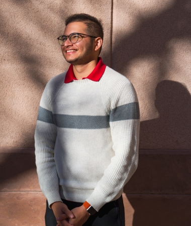 Jiten stands facing the sun against a red brick background