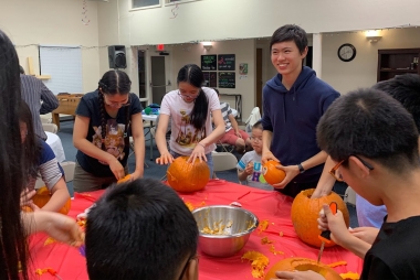 Dennis with a group of students carving pumpkins for Halloween