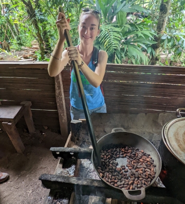 Amrita stirs a pan filled with cocoa beans