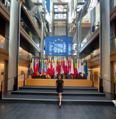 Jennifer stands at the United Nations with an array of international flags behind her